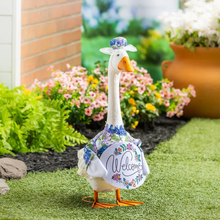 A duck dressed in a shirt and hat stands in green grass, showcasing a whimsical and playful appearance.