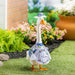 A duck dressed in a shirt and hat stands in green grass, showcasing a whimsical and playful appearance.