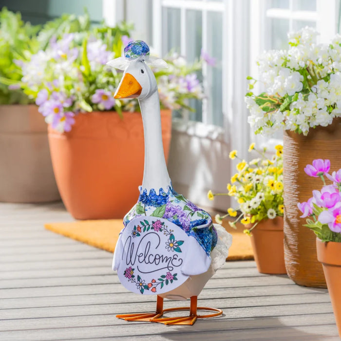 A duck wearing a colorful shirt and hat stands on lush grass, adding a humorous touch to the natural setting.