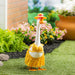 A stylish duck wearing a dress and hat poses in a lush garden surrounded by blooming plants.