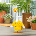 A duck in a bright raincoat stands on a porch, looking curiously at its surroundings.