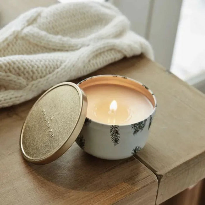 Candle in a decorative container with a wooden lid on a wooden surface