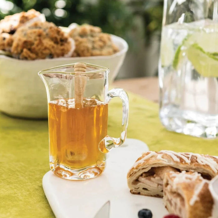 A glass pitcher of tea beside a plate of assorted food items, elegantly arranged on a table setting.