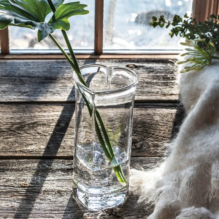 A glass vase with water, showcasing a healthy green plant inside.