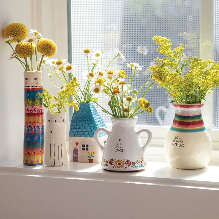 A vibrant bouquet in a vase is placed on a window sill, enhancing the view with its beauty.