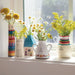 A vibrant bouquet in a vase is placed on a window sill, enhancing the view with its beauty.
