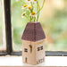 A small house with a vase of daisies on the window sill, brightening the exterior with a touch of nature.