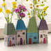 A quaint house featuring a vase of daisies on the window sill, adding charm and color to the scene.