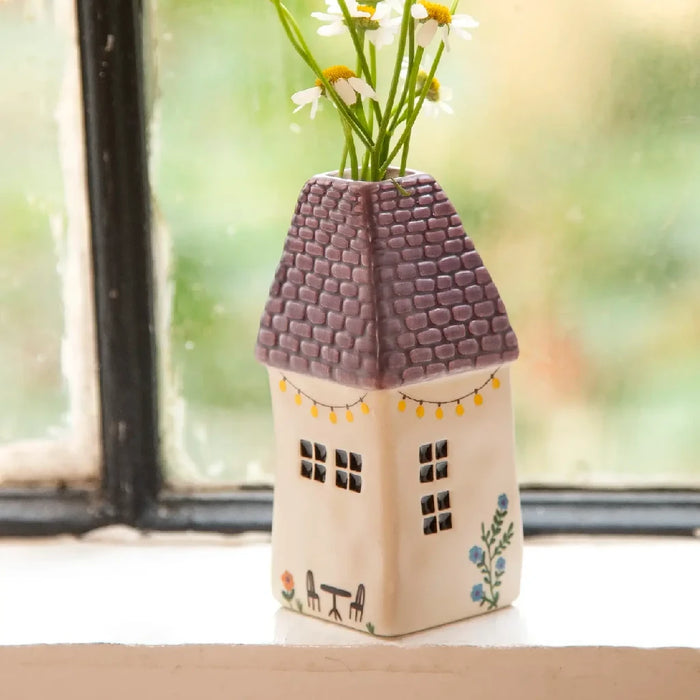 A cozy house with daisies in a vase on the window sill, enhancing the inviting atmosphere of the home.