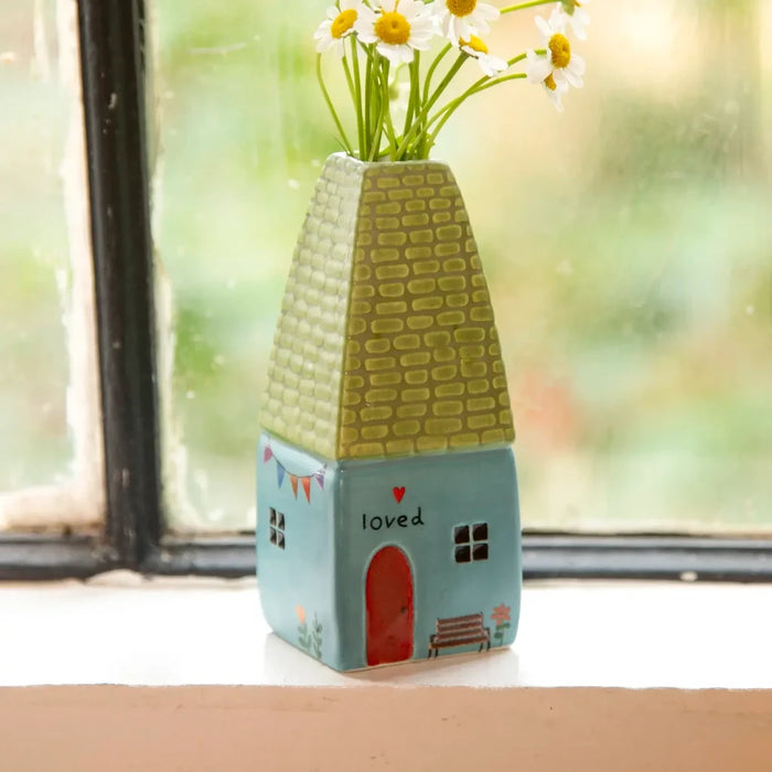 A petite vase adorned with blooming daisies, featuring bright white petals and sunny yellow centers, set against a neutral backdrop.