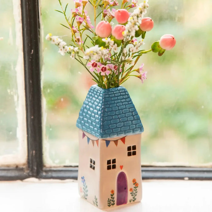 A decorative vase with blooming flowers on a window sill, bringing a touch of nature indoors.