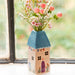 A decorative vase with blooming flowers on a window sill, bringing a touch of nature indoors.