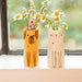 A whimsical yellow dog vase adorned with vibrant daisies, adding a playful touch to the decor.