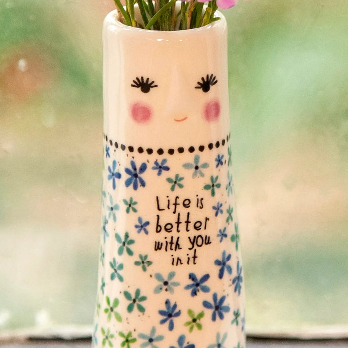 A decorative vase with a variety of flowers on a window sill, adding a touch of nature to the indoor space.