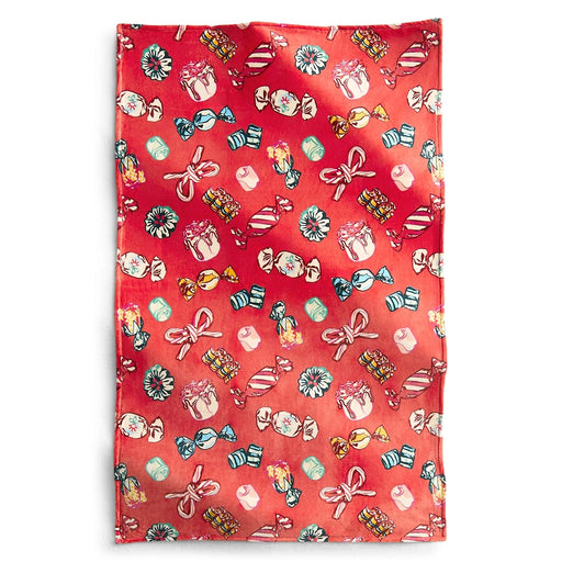A full view of a Vera Bradley plush throw blanket laid flat, featuring a red background with colorful candy, bows, and dessert illustrations scattered across the surface.