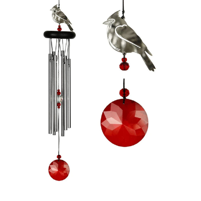 A red and white bird perched near a colorful wind chime swaying gently in the breeze.