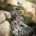 A red and white bird is positioned next to a wind chime, adding charm to the tranquil setting.