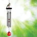A red and white bird alongside a wind chime, enhancing the peaceful ambiance of the garden.