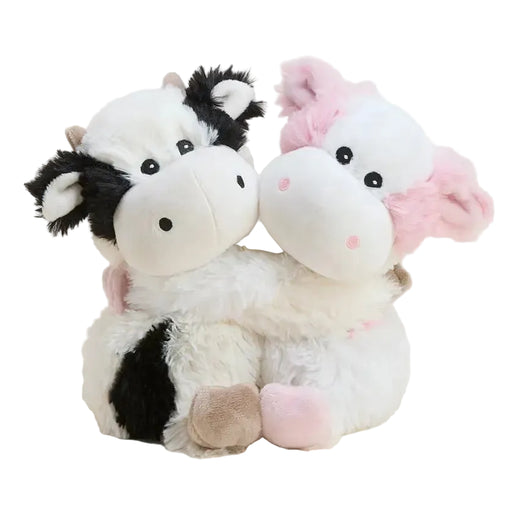 Two cute plush cow toys hugging, one with a black and white pattern and the other with pink accents, set against a plain light beige background.