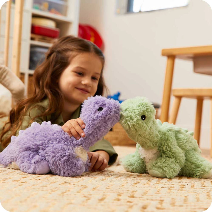 Child playing with Warmies green long neck dinosaur plush heat therapy toy indoors