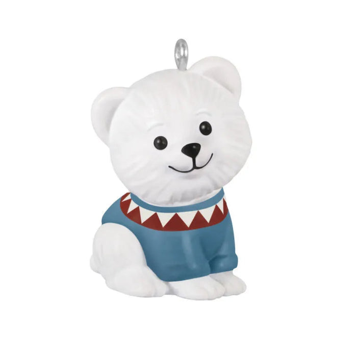 White polar bear ornament wearing a blue sweater with a red and white pattern on a white background