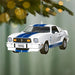 Hanging 1976 Ford Mustang Cobra II ornament on green pine branch with holiday lights