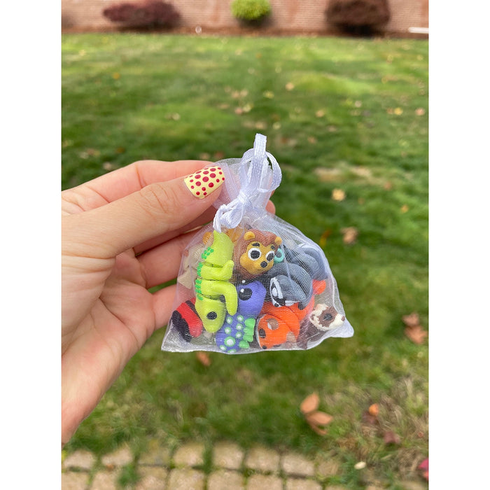 Hand holding a small transparent bag with colorful wiggletz against a grassy background