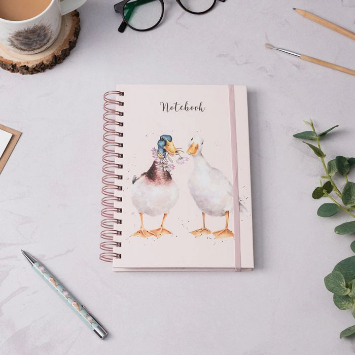 Wrendale Designs 'Not a Daisy Goes By' spiral bound duck notebook displayed on a desk with pen, mug, and greenery, showcasing charming countryside stationery design.