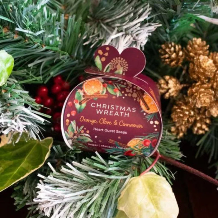 Packaged Christmas wreath soap with festive decorations in the background