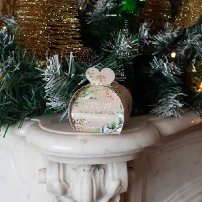 Product packaging with floral design on a decorative stand with Christmas decorations in the background