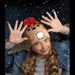 Person wearing a novelty hat with a light on it, surrounded by falling snow.