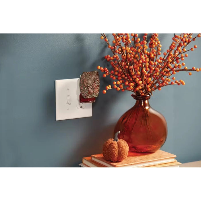 ankee Candle Autumn Leaves Plug-In Fragrance Diffuser in use on a wall outlet beside a fall-themed vase and mini pumpkin.