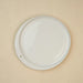 A white plate displayed against a beige wall, highlighting its simplicity and elegance.