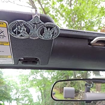 Two metal badges on a car's dashboard with a blurred outdoor background