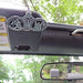 Two metal badges on a car's dashboard with a blurred outdoor background
