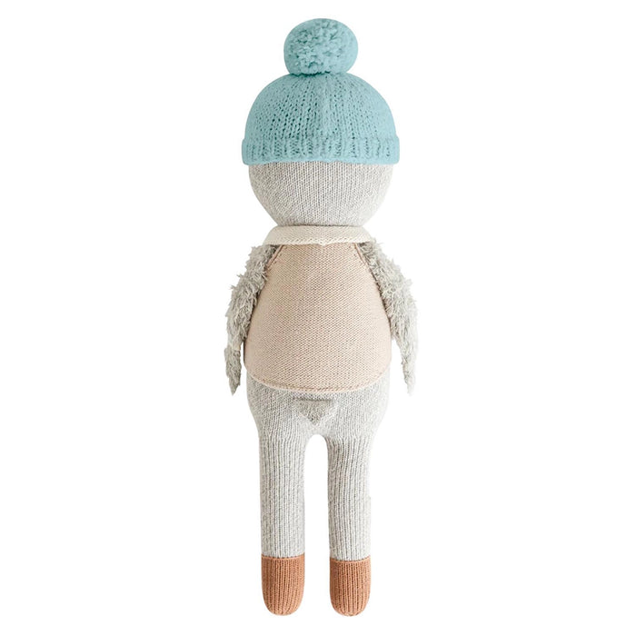 Back view of Greyson the Penguin doll showing light blue hat, beige vest, and soft grey knit body.