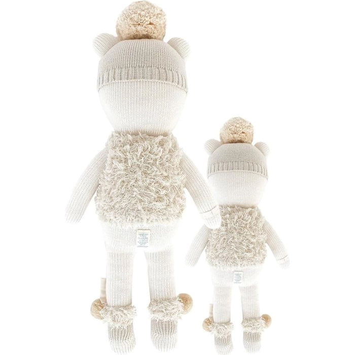 Back view of two Stella the Polar Bear dolls in different sizes, showing the fuzzy knit vest, pom-pom hat, and pom-pom ankle details.
