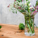 A table adorned with a vase of blooming flowers and a glass of water, enhancing the room's decor.