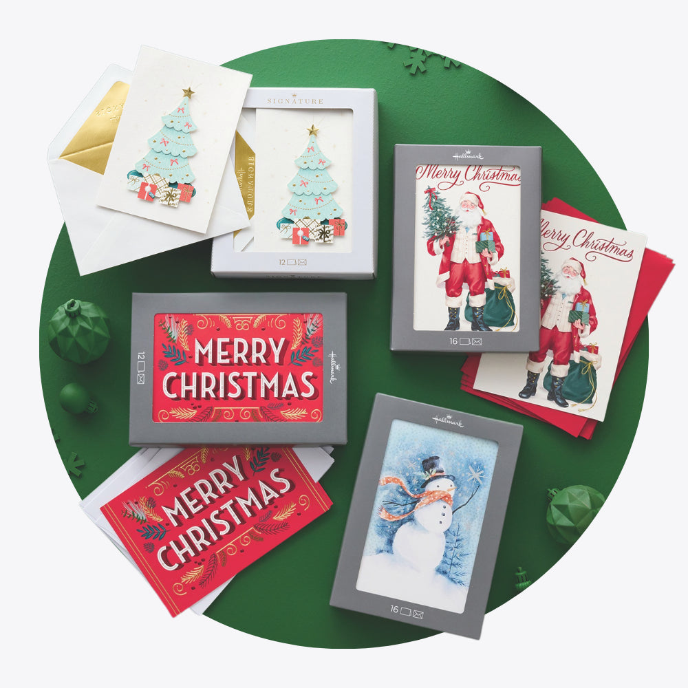 Collection of Hallmark Christmas box cards on a green surface with decorative elements.