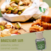 Assorted nuts and caramels with a bottle labeled 'Brazilian Sun' on a wooden surface.