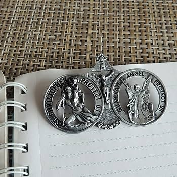 Three silver religious medallions on a notebook page with a textured brown background