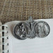 Three silver religious medallions on a notebook page with a textured brown background