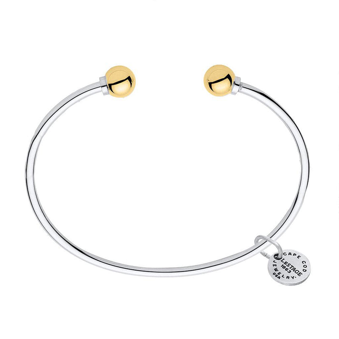 Silver bracelet with gold beads and a tag on a white background