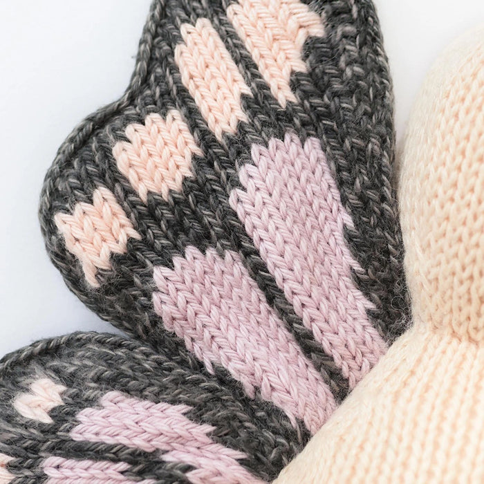 Detailed close-up of Cuddle + Kind Baby Butterfly in Peach wing pattern with pink and peach knit accents.