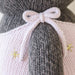 Close-up of pink knit bow and golden embroidered stars on Nova the Kitten’s overalls by Cuddle + Kind.
