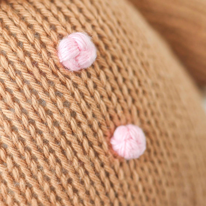 Close-up of hand-embroidered pink buttons on Cuddle + Kind Baby Gingerbread knit holiday doll.