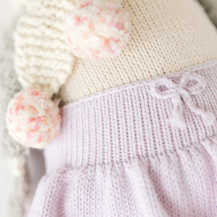 Close-up of Skylar the Penguin doll’s lavender knit skirt waistband with a small knitted bow detail.