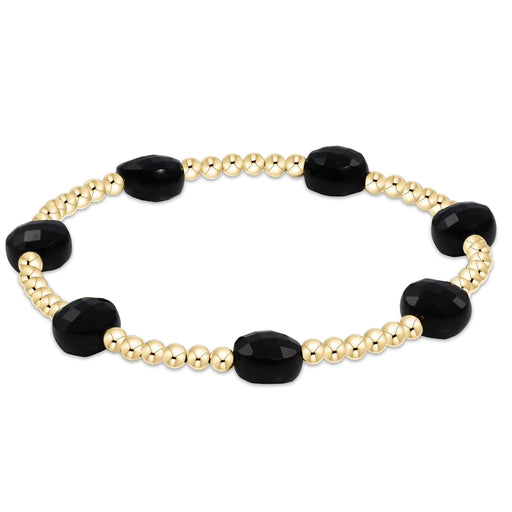 enewton design bracelet with gold beads and black stones on a white background