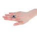 Hand wearing a decorative ring with a blue gemstone on a white background