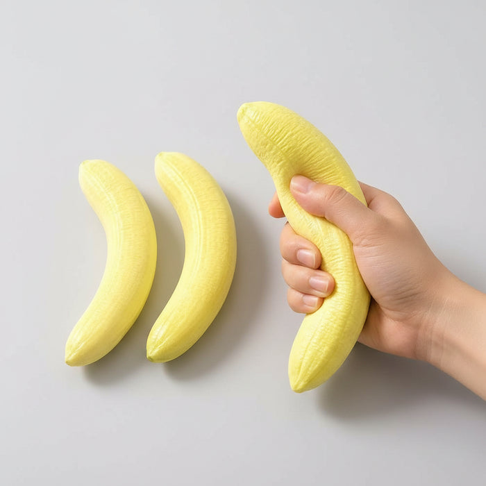 Hand holding a banana next to two bananas on a plate with a wooden tray in the background.